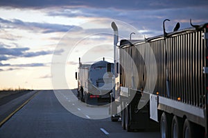 Evening road uphill with convoy semi trucks with bulk trailers