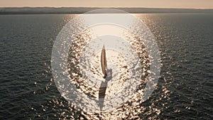 Evening seascape with a yacht with white sails in the open sea aerial view.