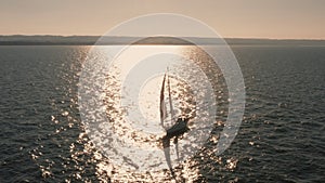 Evening seascape with a yacht with white sails in the open sea aerial view.