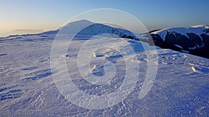 evening shadows on virgin snow on a plateau located on a mountain range