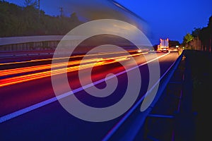 Evening shot of trucks doing transportation and logistics on a highway. Highway traffic - motion blurred truck on a