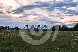 Evening sky over the railway bridge and flowered Bogolyubovo meadow, Vladimir region.