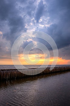 Evening sky,rows of bamboo sticks in the sea and cement bridge near Matchanu Shrine,Phanthai Norasing,Mueang Samut Sakhon District