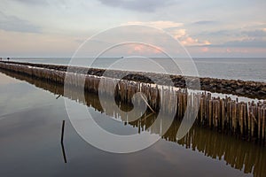 Evening sky,rows of bamboo sticks in the sea and cement bridge near Matchanu Shrine,Phanthai Norasing,Mueang Samut Sakhon District