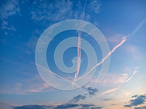 Evening sky with three crossed traces of planes and growing moon