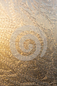 Evening sun and bright blue sky through the frost pattern on the window. Ice pattern and sunlight on winter glass