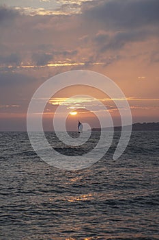 Evening sun over the ocean. Yacht sailing on the horizon rays of sunlight. Bright orange sunset