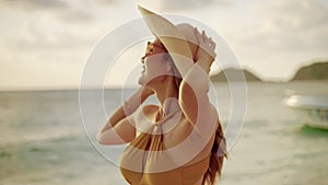 In the evening the sun is sunset, Beautiful Asian girl wearing a sombrero and walking on the beach on her vacation, concept of fre