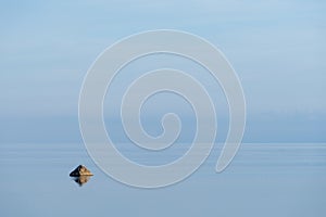 Evening sunlight on the coast, blue sky reflection on the water. Beach in summer. Seaside natural environment background.