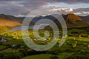 Evening sunlight shining on Cumbrian valley with moody clouds above Crummock Water. Lake District, UK.