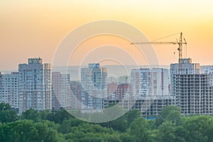 Evening urban landscape of a residential area under construction with a construction crane