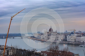 Evening view of the building of the Hungarian Parliament and the Danube in Budapest. Building crane on a beautiful urban backgroun