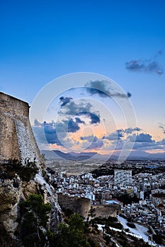 Evening view from the castle of Santa Barbara to the city and the sun sitting down in the mountains. Alicante. Spain.