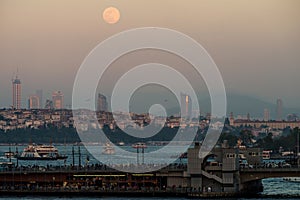 Evening view with the moon on the Bosporus Strait, the Galata Bridge and the Asian part of Istanbul