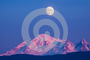 An evening view of Mt Baker under an almost full moon.
