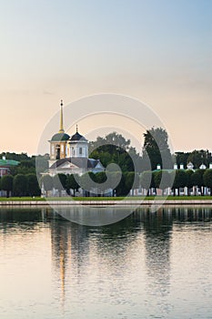 Evening view through the pond on the church with bell tower in museum-estate Kuskovo, Moscow.