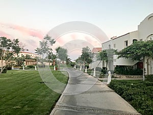 Evening view of the stone path and Arabian Muslim whiteness of building, cottages amidst the tropical green of palm trees and pla