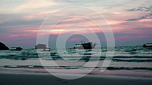 Evening waves. Water is coming. In turbulent waves, the silhouette of a man kayaking. Boats sway violently. The sky is reddish ora