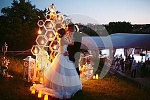 Evening wedding ceremony. The bride and Groom are on the background of the wedding arch.