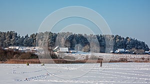 Evening on winter lake. Silhouettes of fishermen on ice background