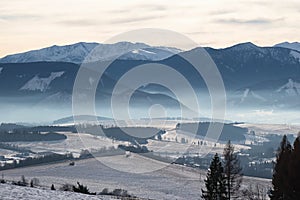 Evening winter landscape under Low Tatras mountains with some low evening fog present.