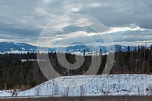 Evening winter mountain ridge and sun rays from cloudy sky