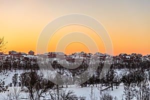 Evening winter sunset over suburban houses on horizont. Belgorod Region, Russia.