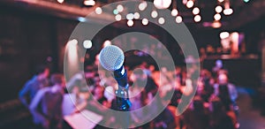 Event hall: Close up of microphone stand, seats with audience in the blurry background