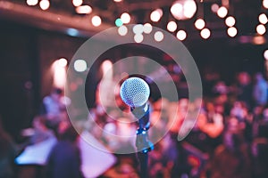 Event hall: Close up of microphone stand, seats with audience in the blurry background