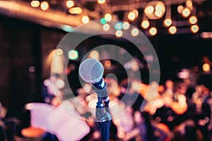 Event hall: Close up of microphone stand, seats with audience in the blurry background