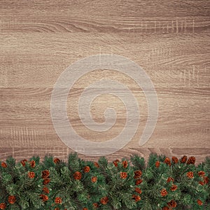 Evergreen fir branches on brown wooden texture background.