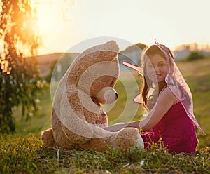 Every day is an adventure when youre little. Portrait of a cute little girl playing with a huge teddybear in the park.