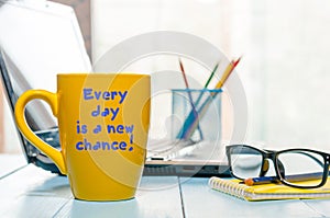 Every day is a new chance. Motivate text on morning coffee cup at business office background