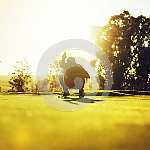 Every golf player is as good as his last putt. a young man eyeing up the putt during a round of golf.