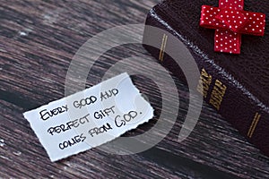 Every good and perfect gift comes from God, handwritten quote with holy bible book on wood