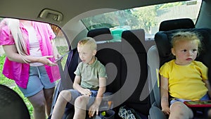 Before every trip, a woman responsibly puts her children in car seats.