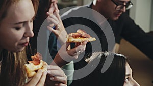 Everybody laughing, chatting having great time together. Happy group of friends sharing pizza. One girl stealing piece