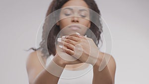 Everyday beauty procedures. Young defocused african american lady applying hand cream on palms, focus on female hands