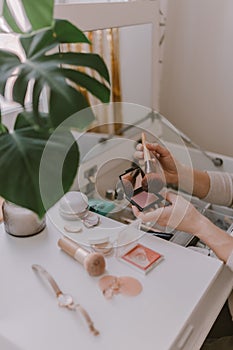 Everyday beauty routine. Make up artist. Dressing vanity. Women`s hands. Pastel colors. In front of the mirror. Palettes, brushes
