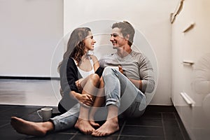 Everyday I love you more and more. an affectionate young couple sitting on the kitchen floor.