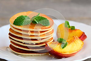 Everyday pancakes with syrup and grilled fruit on a serving plate. Pancake recipe without baking powder. Breakfast idea