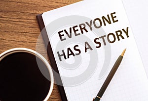 EVERYONE HAS A STORY - text on notepad on wooden desk