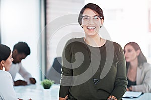 Everyone loves a great leader. Portrait of a businesswoman in an office with her colleagues in the background.