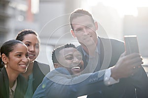 Everyone smile for the selfie. a group of businesspeople taking a selfie against a city background.