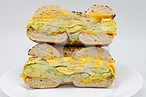 Everything Bagel Cut in Half with Avocado Eggs and Cheese on a White Plate