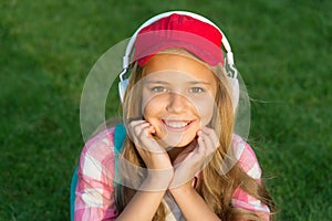 Everything is cool. Cool kid listen to music on green grass. Happy child use headphones outdoors. Cool relaxing music