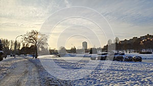 Everything is covered with snow after the winter snowfall. The footpath has been cleared. The river is under ice. Buildings stand