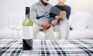 Everything goes well with a bottle of wine. an unrecognizable senior couple relaxing on a sofa with their bottle of wine