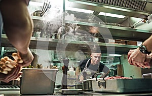 Is everything ok Surious chef is looking how his assistants are cooking a meat in a restaurant kitchen