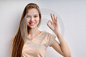 Everything will be OK. good-looking teenage girl with long hair showing ok gesture